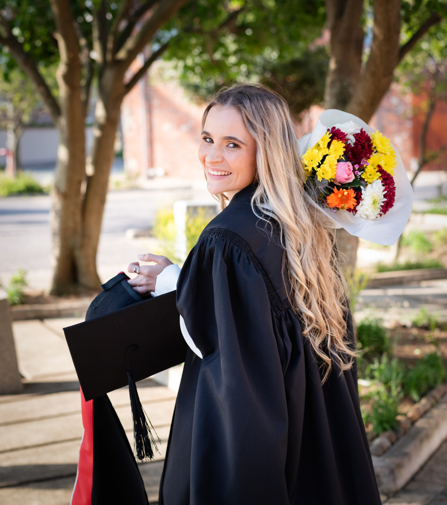 A Graduation Photography session at Ushaka Marine World in Durban with a Happy Graduate carrying a Boquete of Yellow Flowers